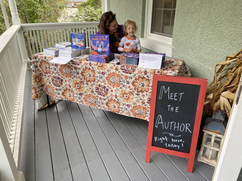 Tracy with her daughter Ava with a table of books on the porch of The Ivy Bookshop